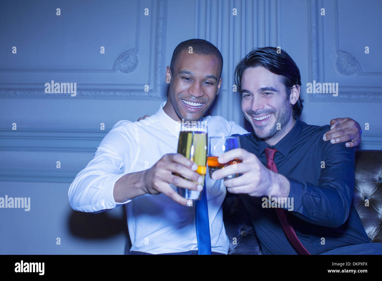 Les hommes bien habillés hugging and toasting beer and cocktail Banque D'Images