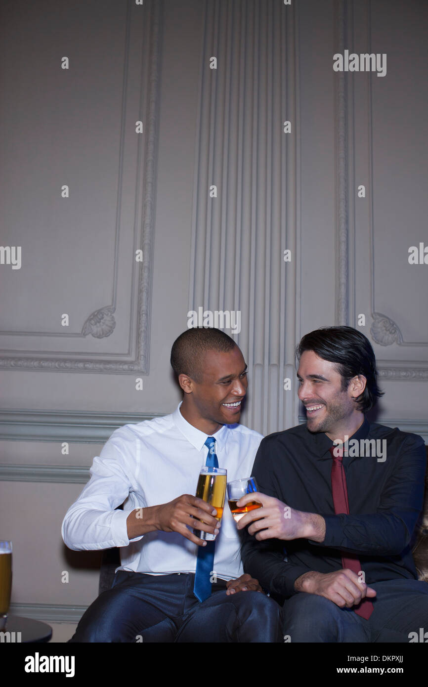 Bien habillé men toasting beer et cocktails Banque D'Images