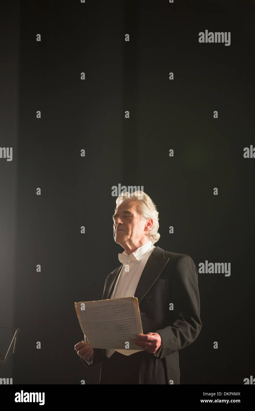 Le calme d'orchestre holding sheet music avec les yeux fermé Banque D'Images
