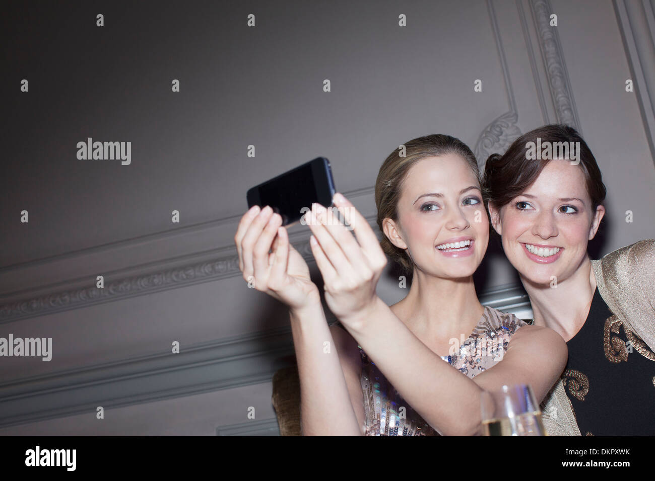 Smiling women taking self-portrait with camera phone Banque D'Images