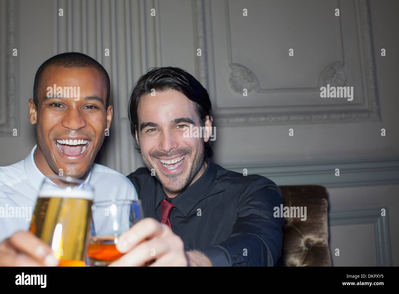 Close up portrait of smiling men toasting beer and cocktail Banque D'Images
