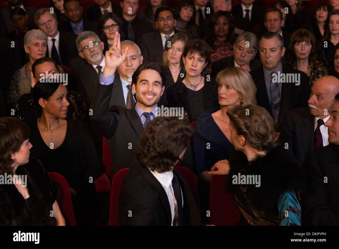 Man raising hand in theater audience Banque D'Images
