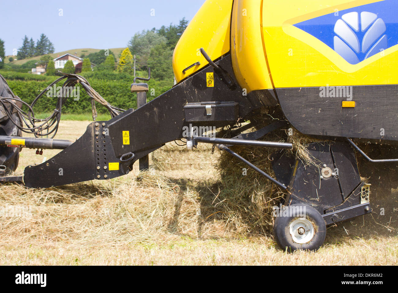Pick-up d'un nouveau big-Holland ramasseuse-presse de la place de la mise en balles de foin sur une ferme biologique. Powys, Pays de Galles. Juillet. Banque D'Images