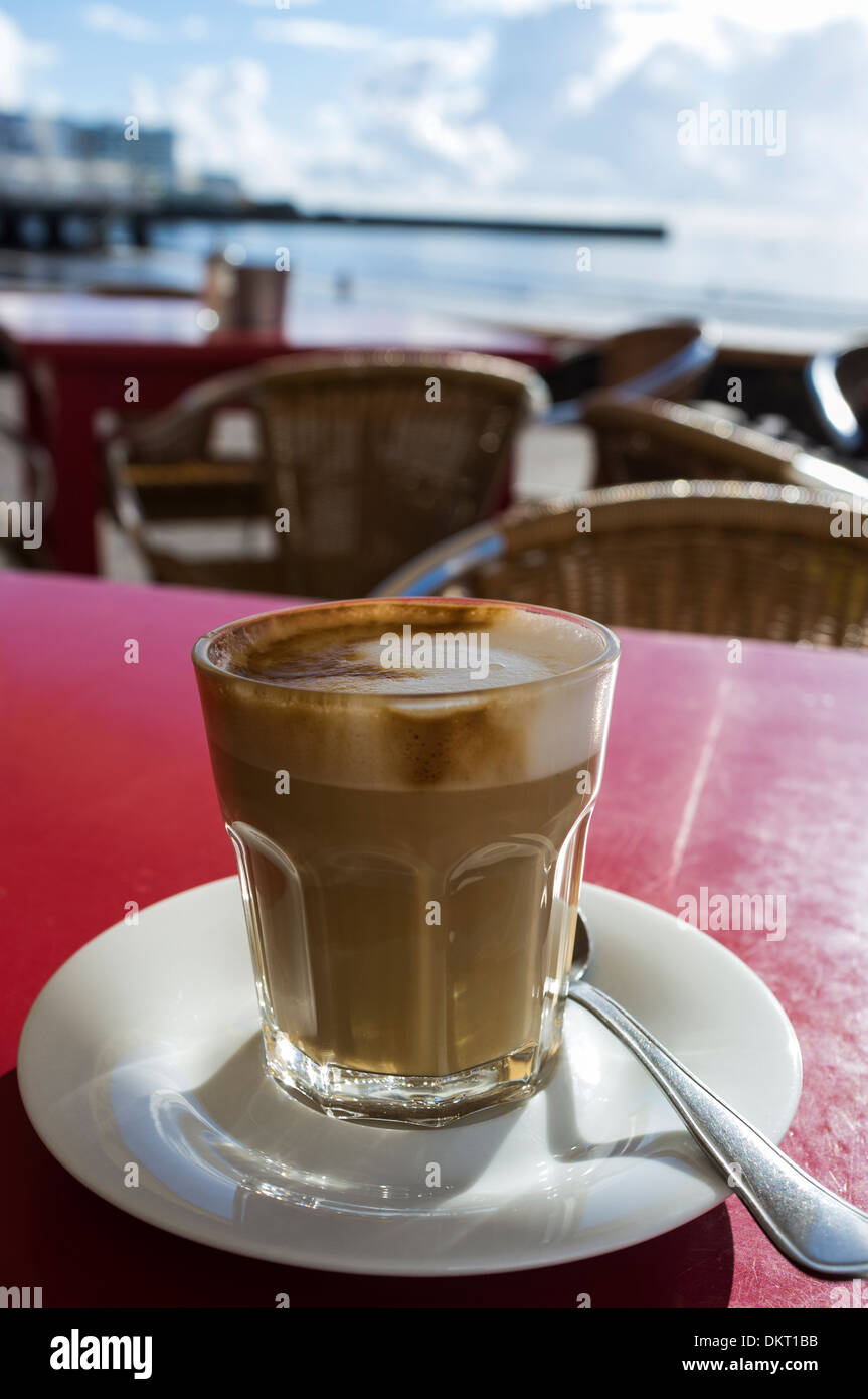 Cafe con leche dans un verre à une terrasse extérieure cafe à El Medano, Tenerife, Canaries, Espagne. Banque D'Images