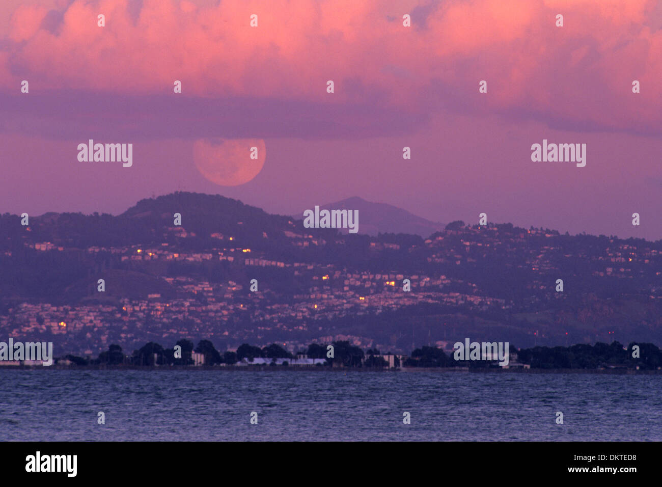 La pleine lune au coucher du soleil sur l'Oakland Hills et Mount Diablo, vu de Rincon, San Francisco, Californie Banque D'Images