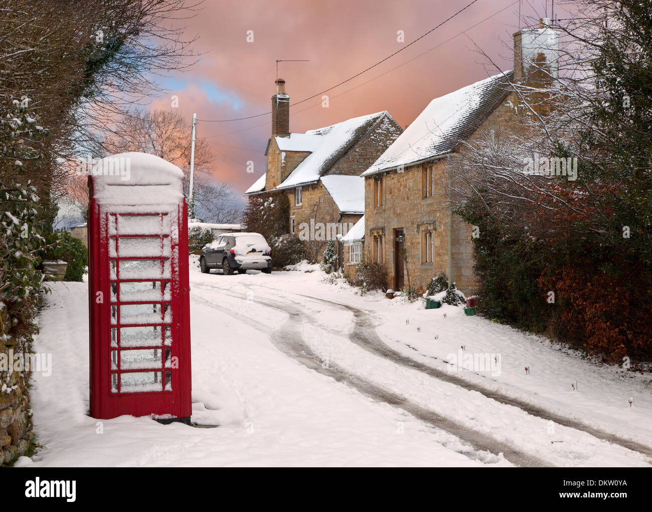 Boîte de téléphone rouge et cottages dans la neige, Cotswolds, Gloucestershire, Angleterre. Banque D'Images