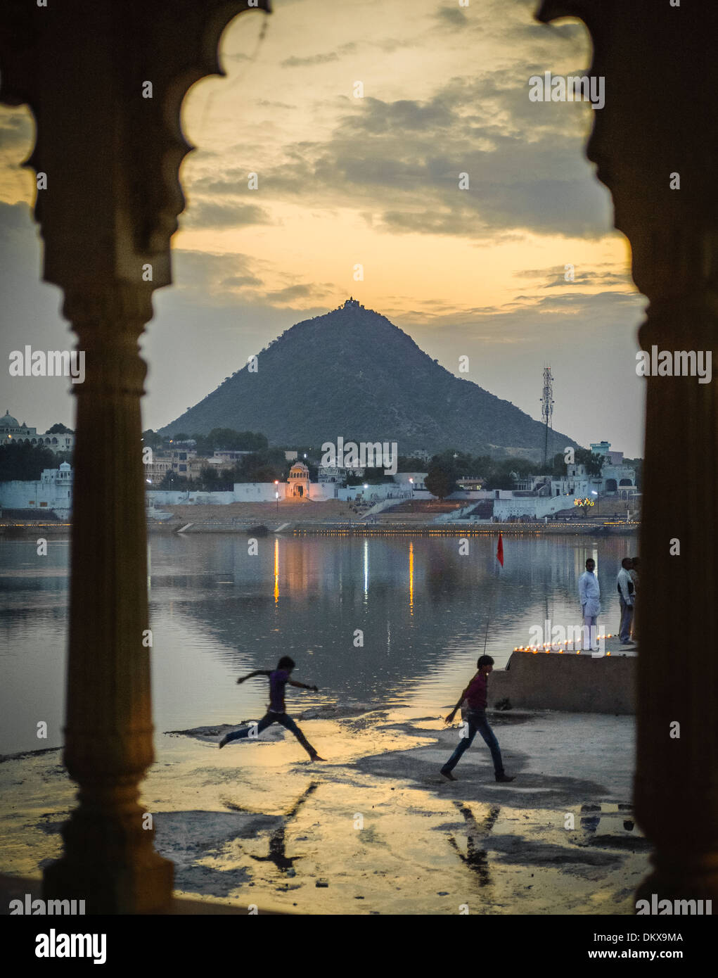 Garçon sautant par-dessus le lac sacré près de flaque au cours de Pushkar Camel juste. Banque D'Images