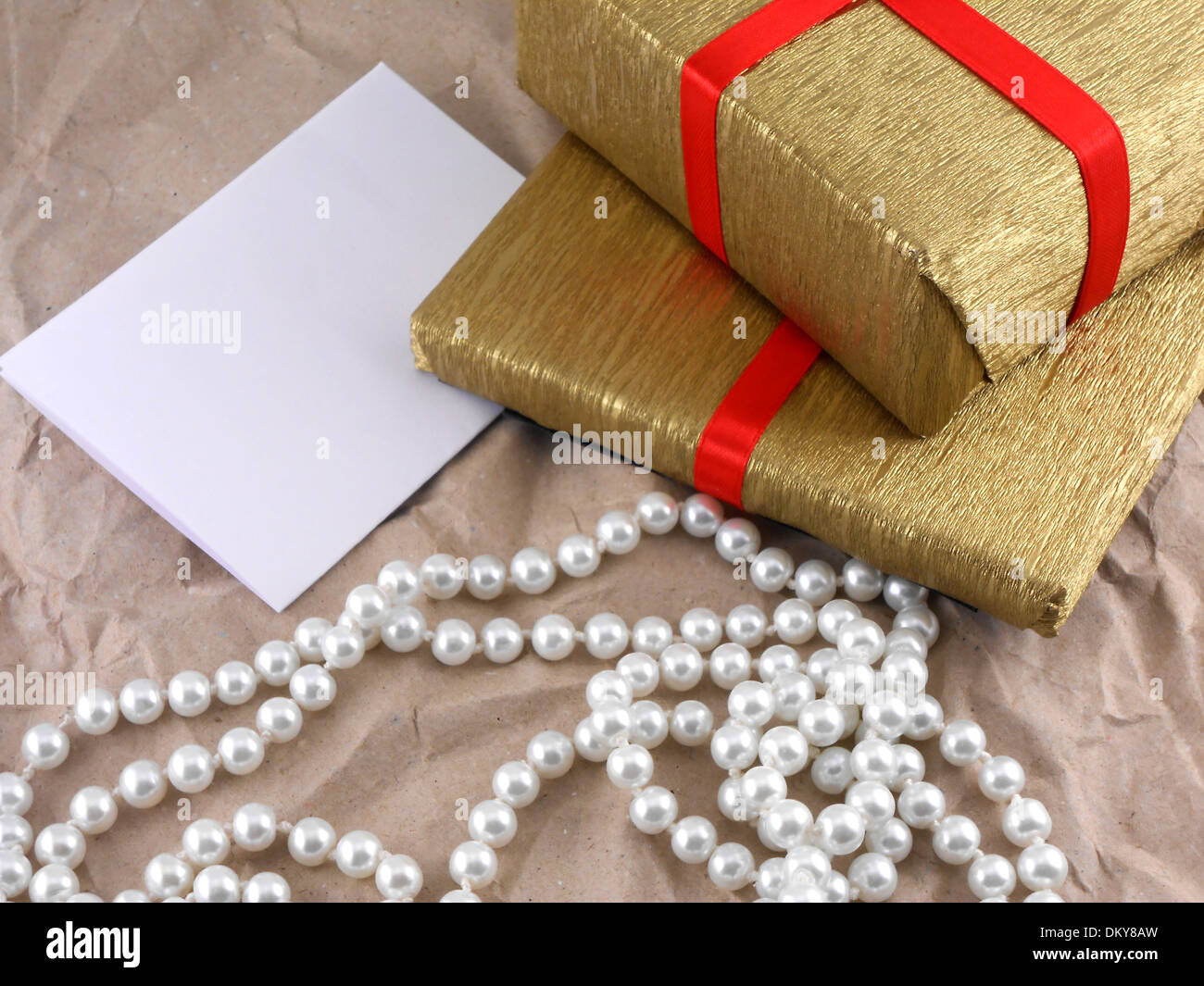 Boîte cadeau doré avec arc rouge avec perles sur vieux papier Banque D'Images