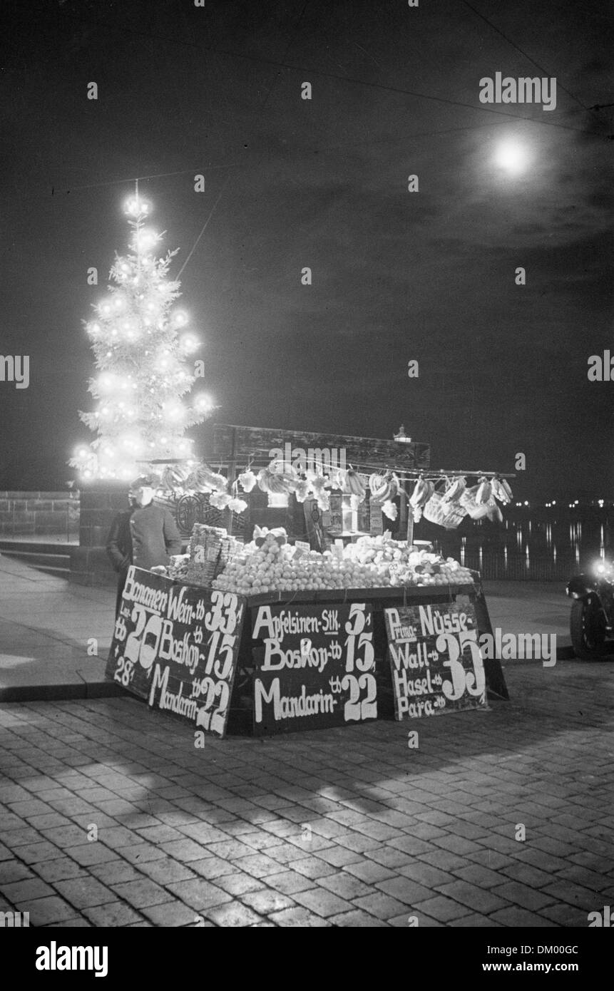 Vue d'un stand vendant des fruits devant un sapin Noël à Dresde, Allemagne, sans date (4091, 1935). Les prix des pommes et noix sont écrits sur le décrochage. Photo : Deutsche Fotothek/Richard Petersen Banque D'Images