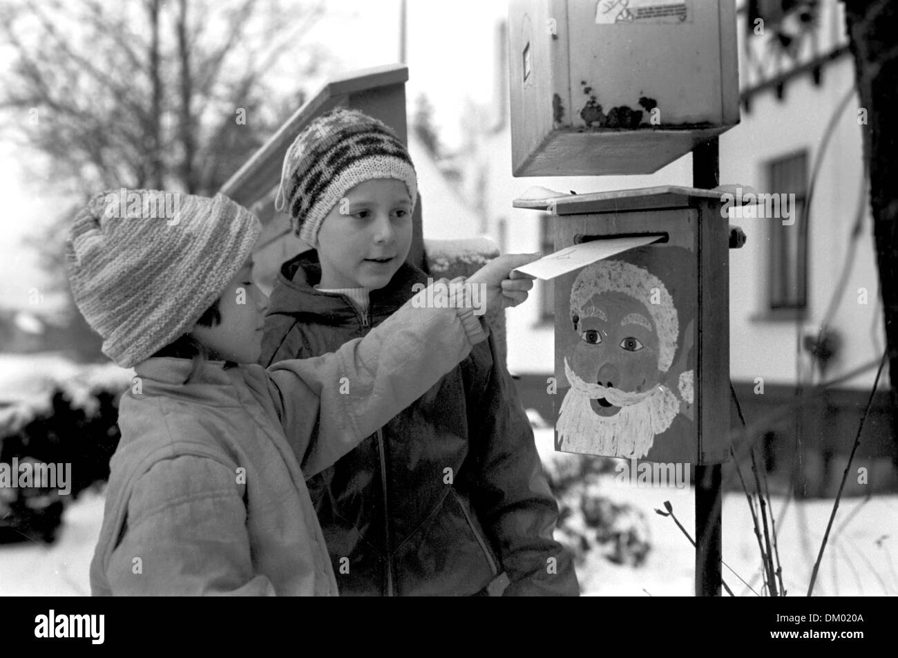 Deux enfants poster une lettre avec une liste de souhaits au Père Noël dans une boîte aux lettres, qui est attaché à un poteau dans une boîte aux lettres normales, en décembre 1988. Photo : Wolfgang Thieme Banque D'Images