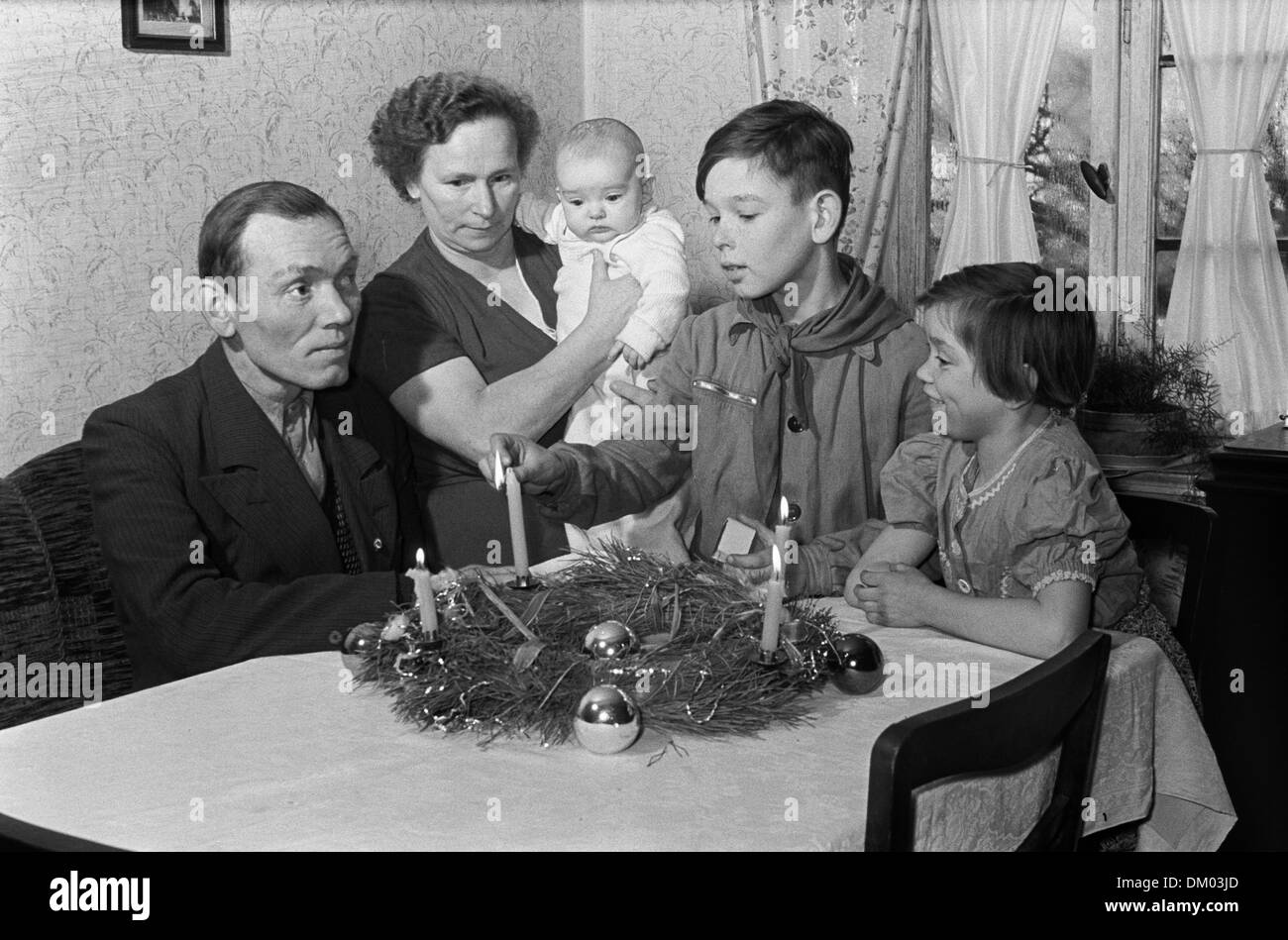 Une famille de trois enfants est représenté à une table avec une guirlande et un garçon allume la bougie de l'avent quatrième, en 1955. Photo : Deutsche Fotothek/Rössing Banque D'Images