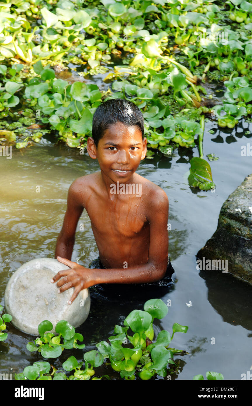 Un jeune garçon indien un pan d'aluminium laver dans la rivière, le Kerala backwaters, Sud de l'Inde Banque D'Images