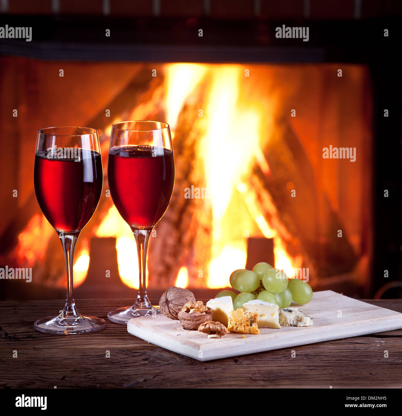 La vie encore romantique près de la cheminée. Verres de vin, fromage et noix. Banque D'Images
