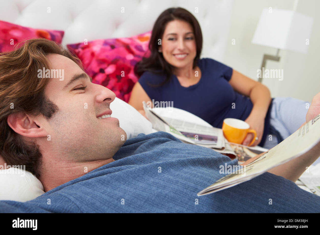 Couple Relaxing In Bed avec café et lire la presse Banque D'Images