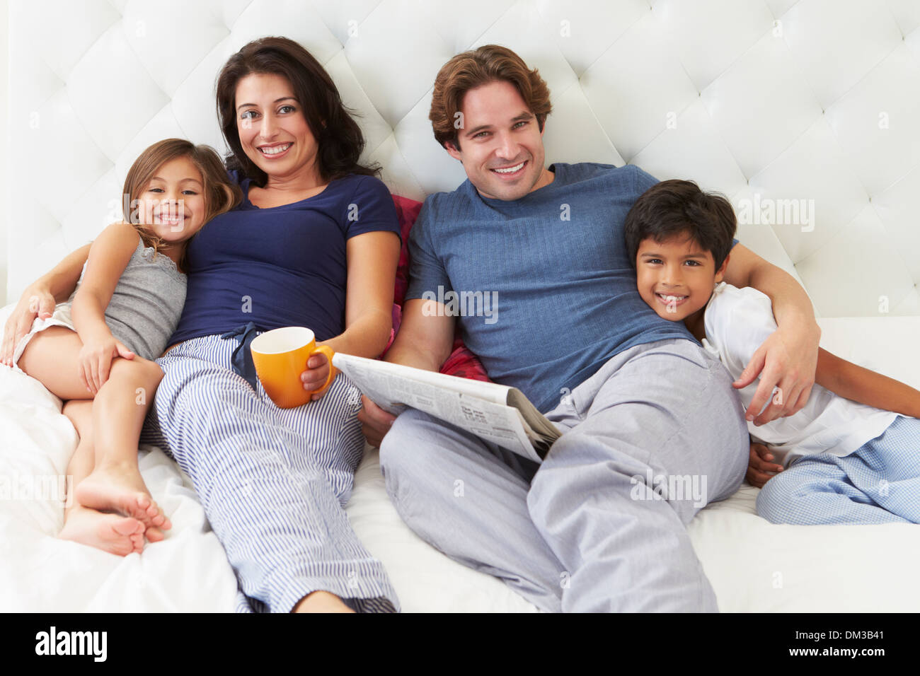 Family Relaxing In Bed avec café et lire la presse Banque D'Images