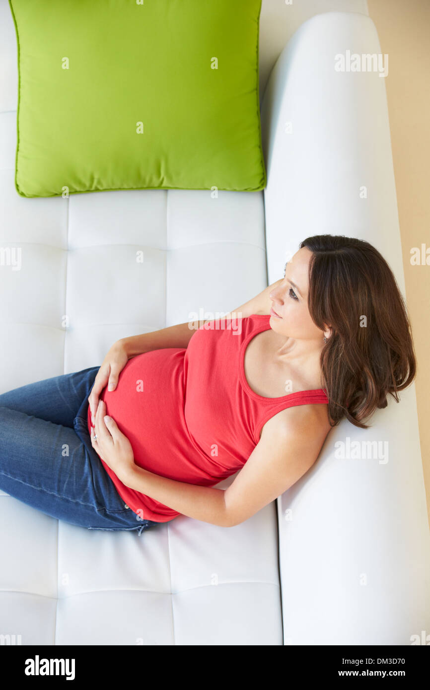 Vue de dessus de femme enceinte Relaxing On Sofa Banque D'Images Vue de dessus de femme enceinte Relaxing On Sofa Banque D'Images