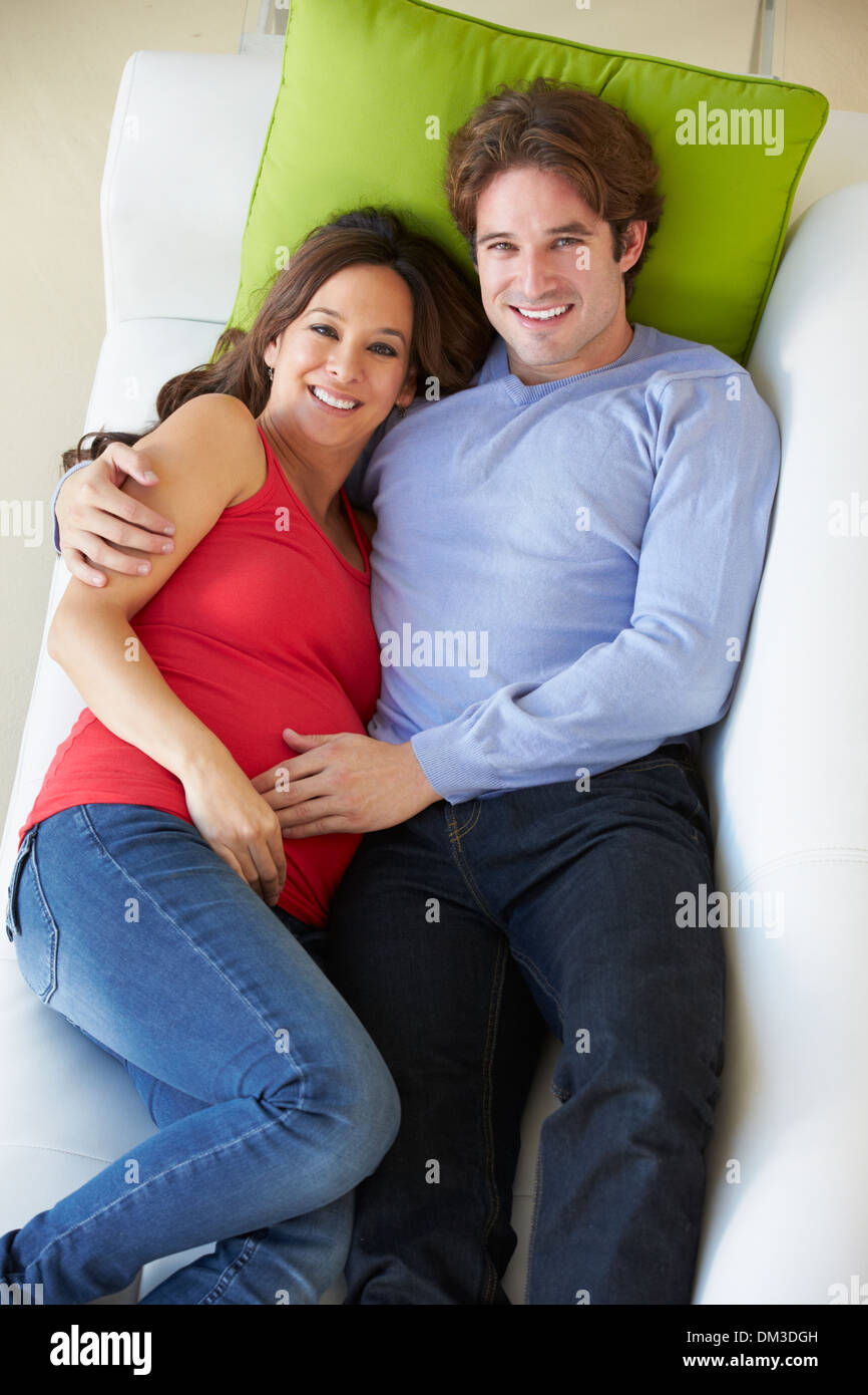 Vue aérienne de Man Relaxing On Sofa with Pregnant Wife Banque D'Images Vue aérienne de Man Relaxing On Sofa with Pregnant Wife Banque D'Images