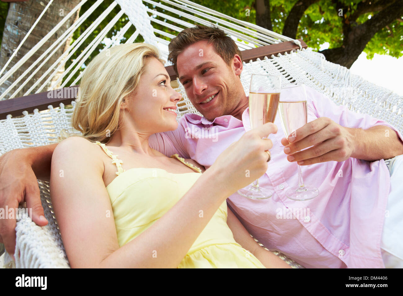 Couple Relaxing In Hammock Beach Drinking Champagne Banque D'Images