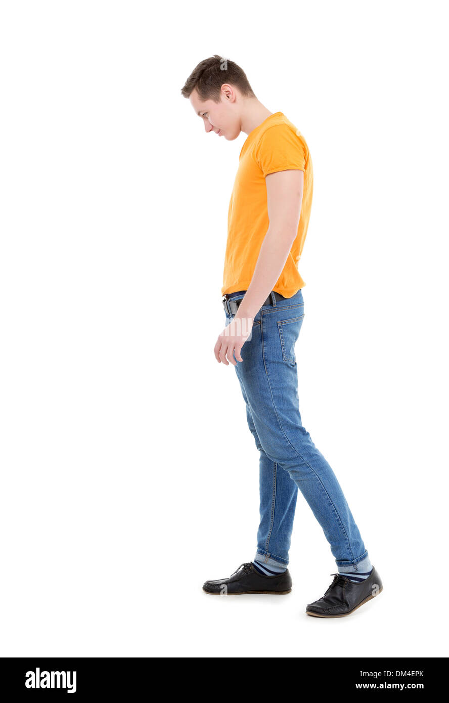 Jeune homme, vêtu d'un T-shirt jaune et un Jean slim, debout sur fond blanc Banque D'Images