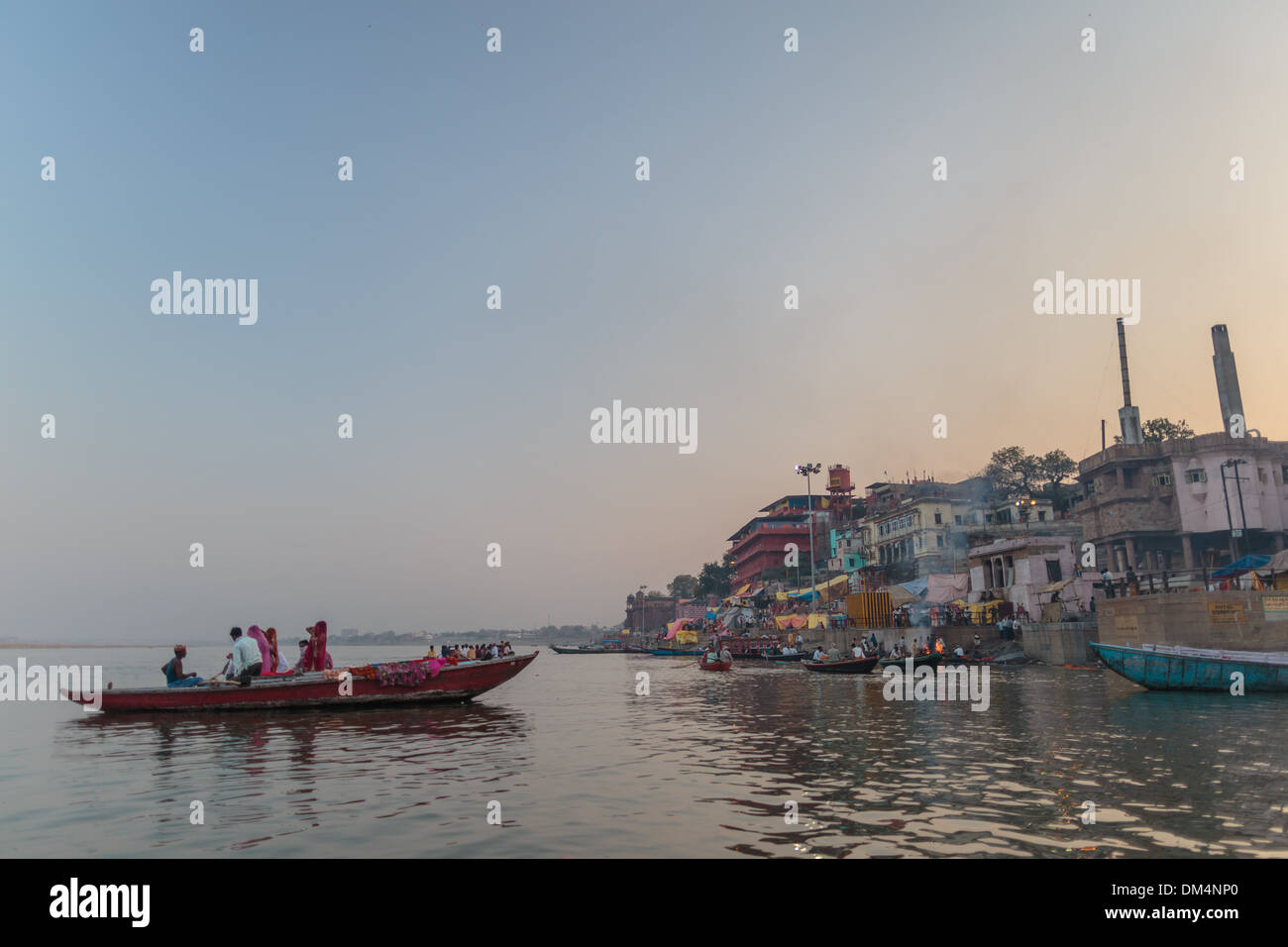 Un bateau plein de touristes femmes hindoues flotte sur le Gange sacré à Varanasi au coucher du soleil près de la gravure de Manikarnika ghat. Banque D'Images Un bateau plein de touristes femmes hindoues flotte sur le Gange sacré à Varanasi au coucher du soleil près de la gravure de Manikarnika ghat. Banque D'Images