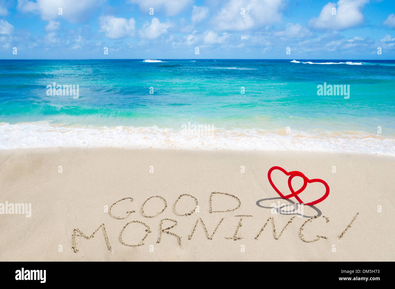 Inscription 'Bonjour' avec deux cœurs sur la plage de sable à l'océan Banque D'Images