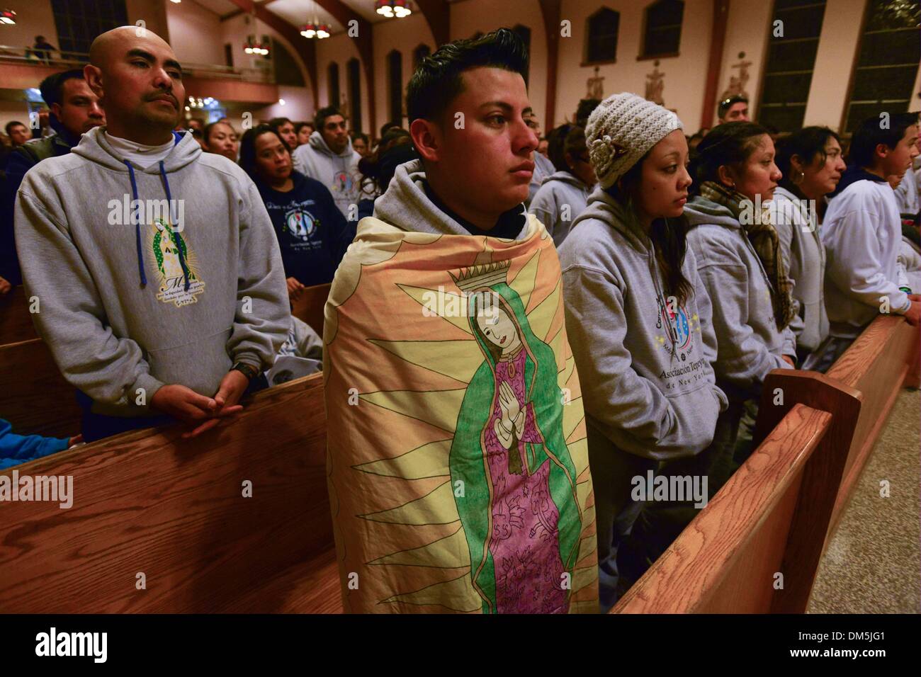 Garfield, New Jersey, USA. Dec 11, 2013. MIGUEL A. Garcia, de Puebla, Mexique et un résident de Garfield, apporte un portrait de la Vierge de Guadalupe à être béni par le Père William Riley à la Sainte Église catholique au nom de Garfield, New Jersey, la dernière étape pour les pèlerins sur un 87 jours, 2 700 milles de course au flambeau du relais qui a commencé dans le centre-sud de l'état de Puebla, au Mexique et se termine à la cathédrale Saint-Patrick de New York. Banque D'Images