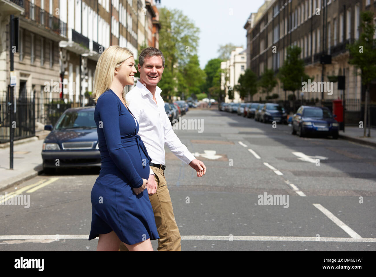 Couple avec femme enceinte Crossing City Road Banque D'Images