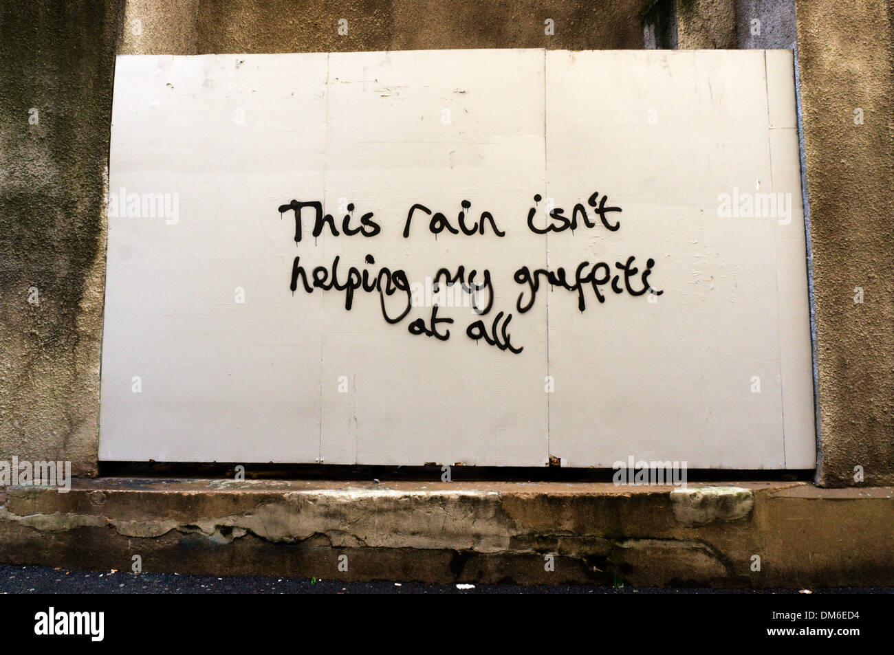 'Cette pluie n'aide pas du tout' graffiti mon message sur un mur à Bristol. Banque D'Images