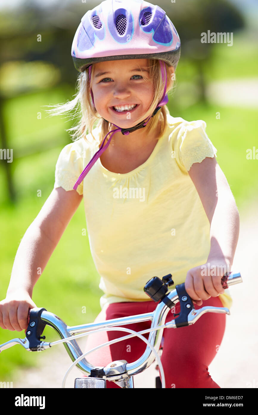 Young Girl Riding Bike le long de la voie de Pays Banque D'Images