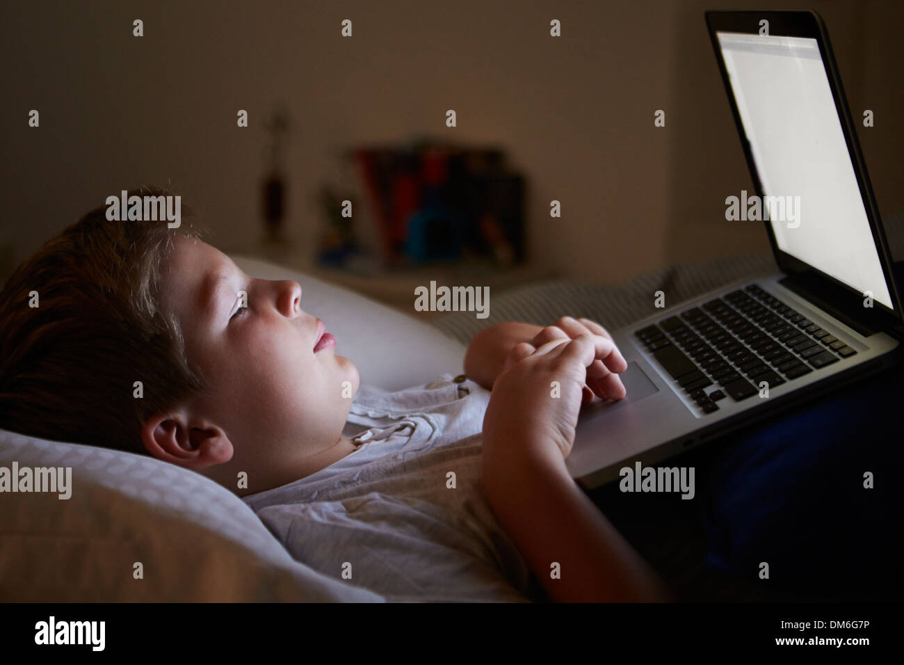 Boy Using Laptop In Bed at Night Banque D'Images
