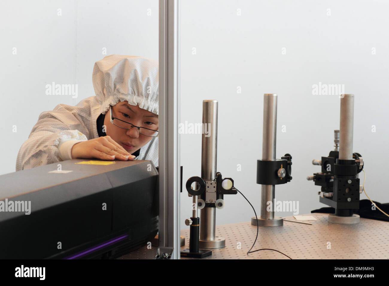 L'Asie une femme scientifique travaille dans un laboratoire de l'holographie avec manteau en salle blanche de l'installation de nouvelles technologies voir un laser Banque D'Images