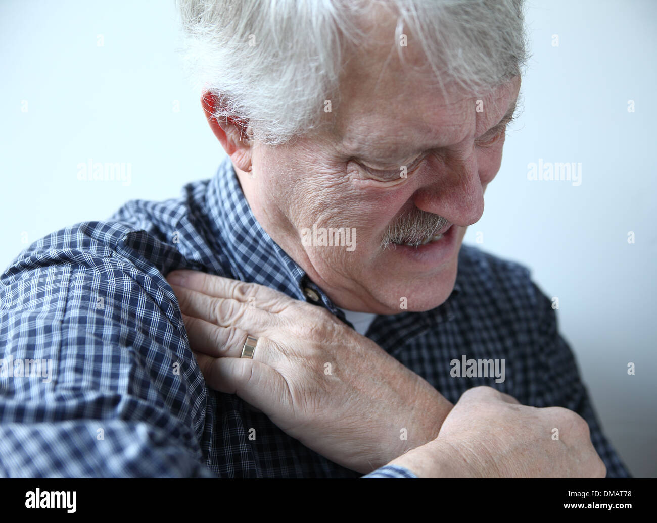 Homme plus âgé grimaces et touche domaine de la douleur dans son épaule Banque D'Images