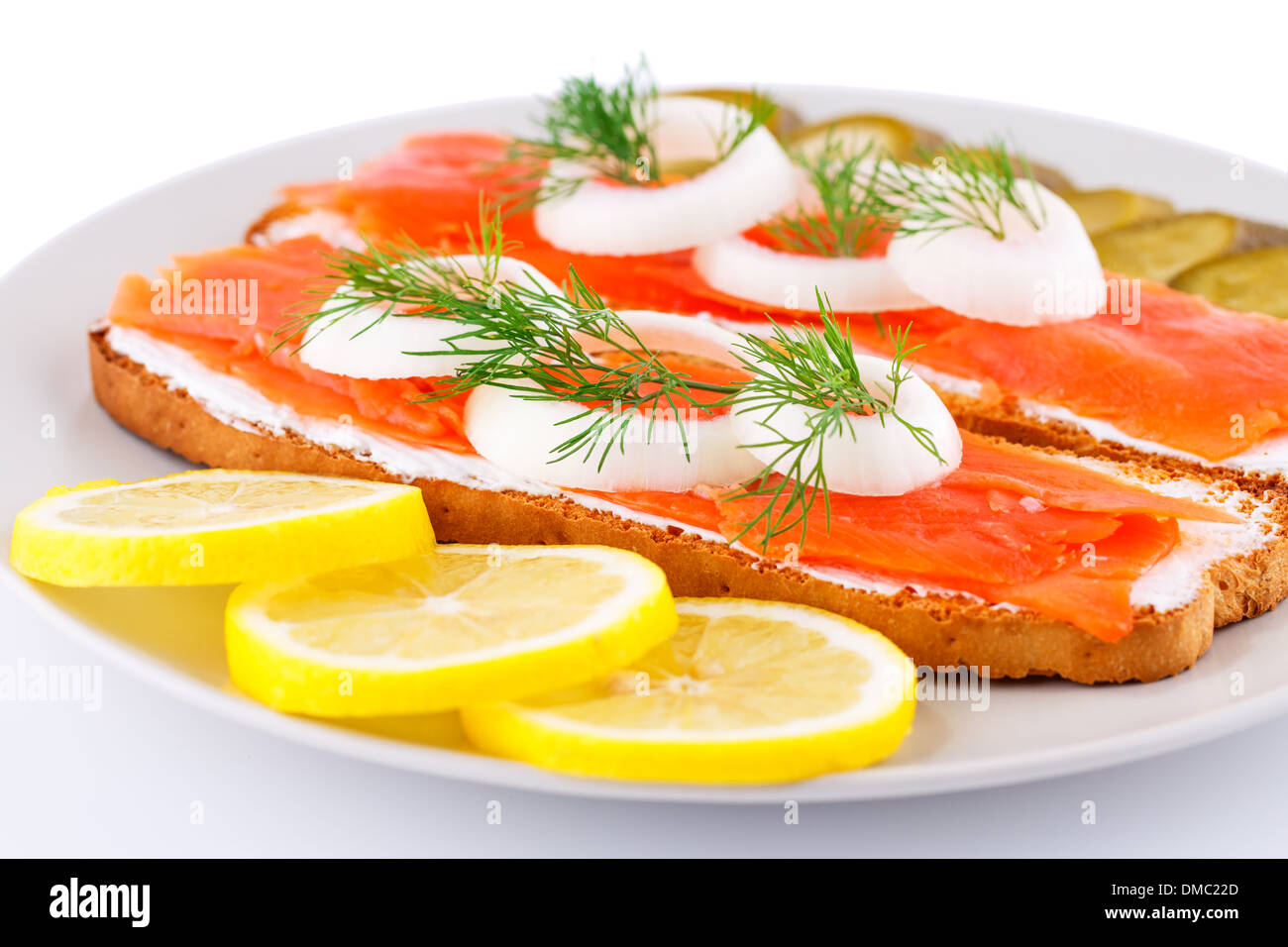 Sandwiches au saumon mariné avec le concombre, l'oignon, l'aneth et citron sur la plaque libre de droit. Banque D'Images