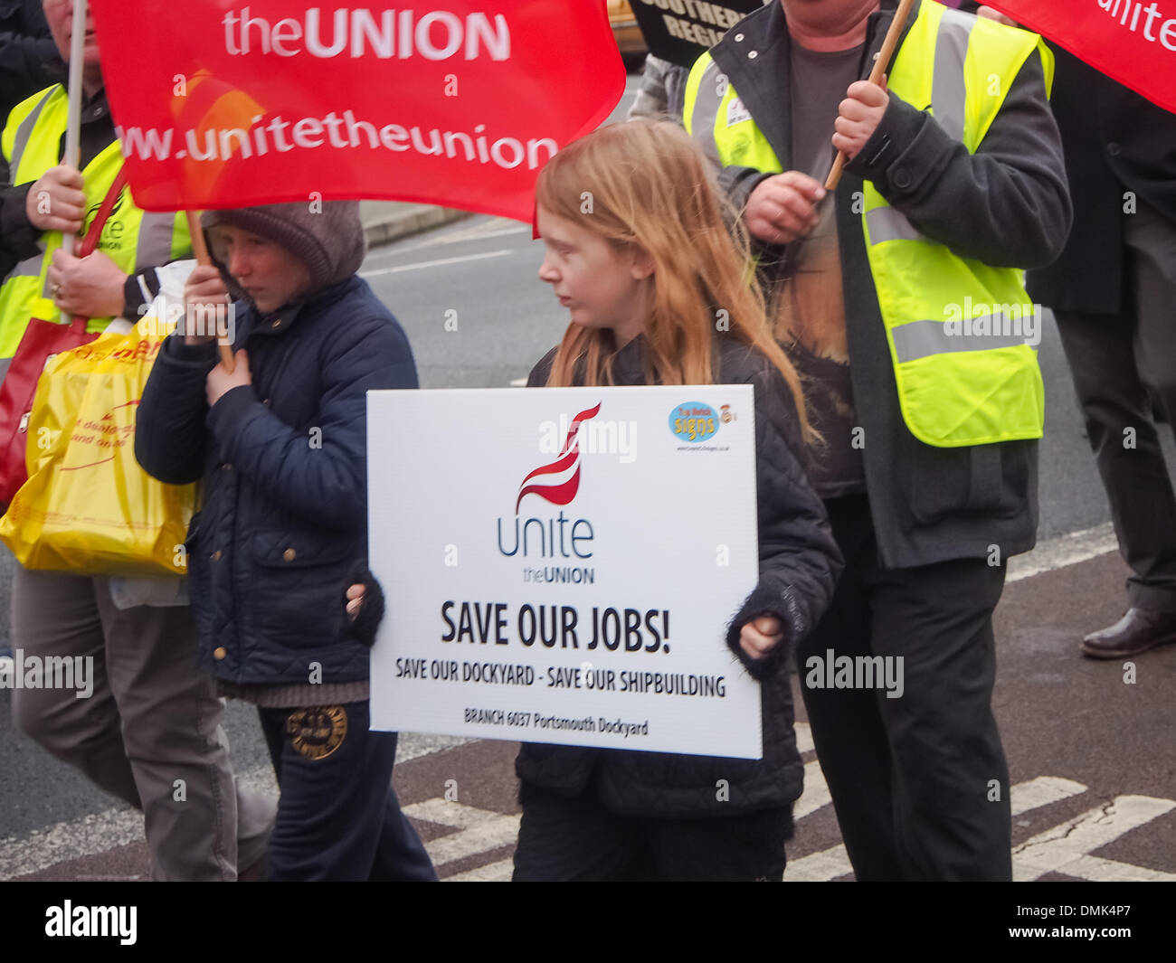 Portsmouth, Royaume-Uni. 14 décembre 2013. Une jeune fille porte une inscription acte de 'Save nos travaux' au cours d'une protestation contre la possible fermeture de l'usine de construction navale de BAE à Portsmouth Crédit : Simon Evans/Alamy Live News Banque D'Images