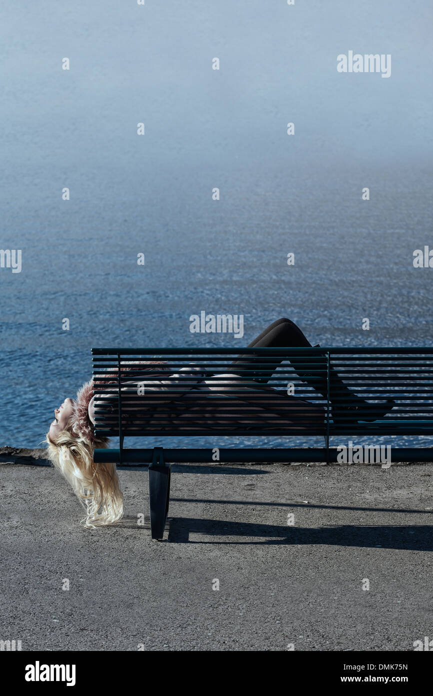 Une fille dans une robe rose est allongé sur un banc au bord de la mer Banque D'Images