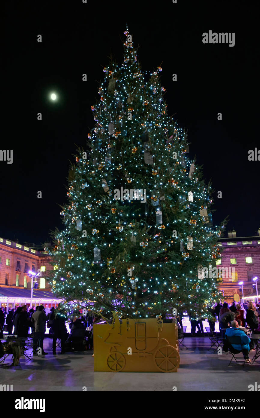 Nuit et lune dans la cour de Somerset House avec décorations d'arbres de Noël et personnes autour de la patinoire extérieure du Strand London England UK Banque D'Images