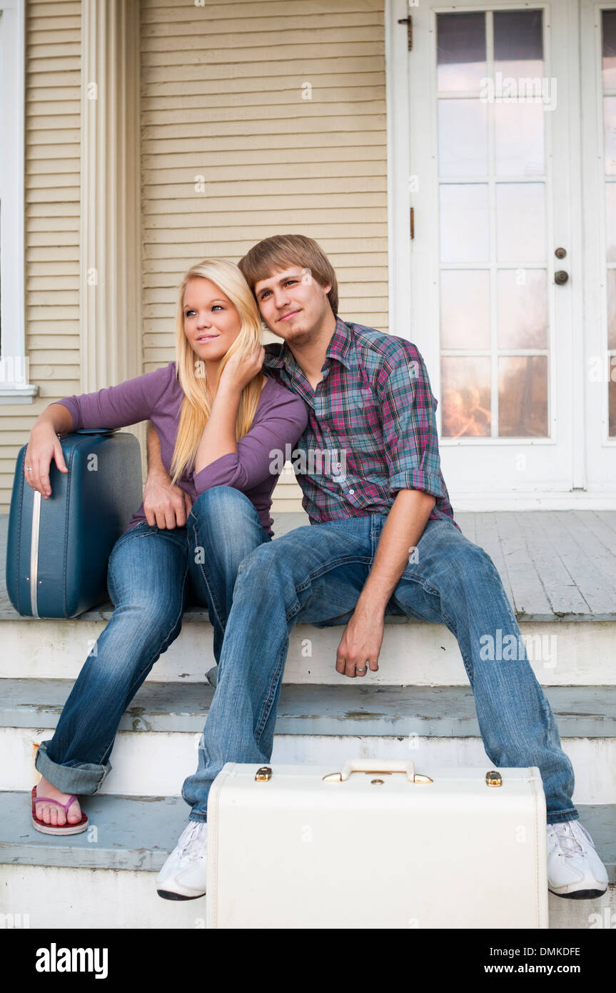 Young couple sitting on steps avec des valises. Banque D'Images