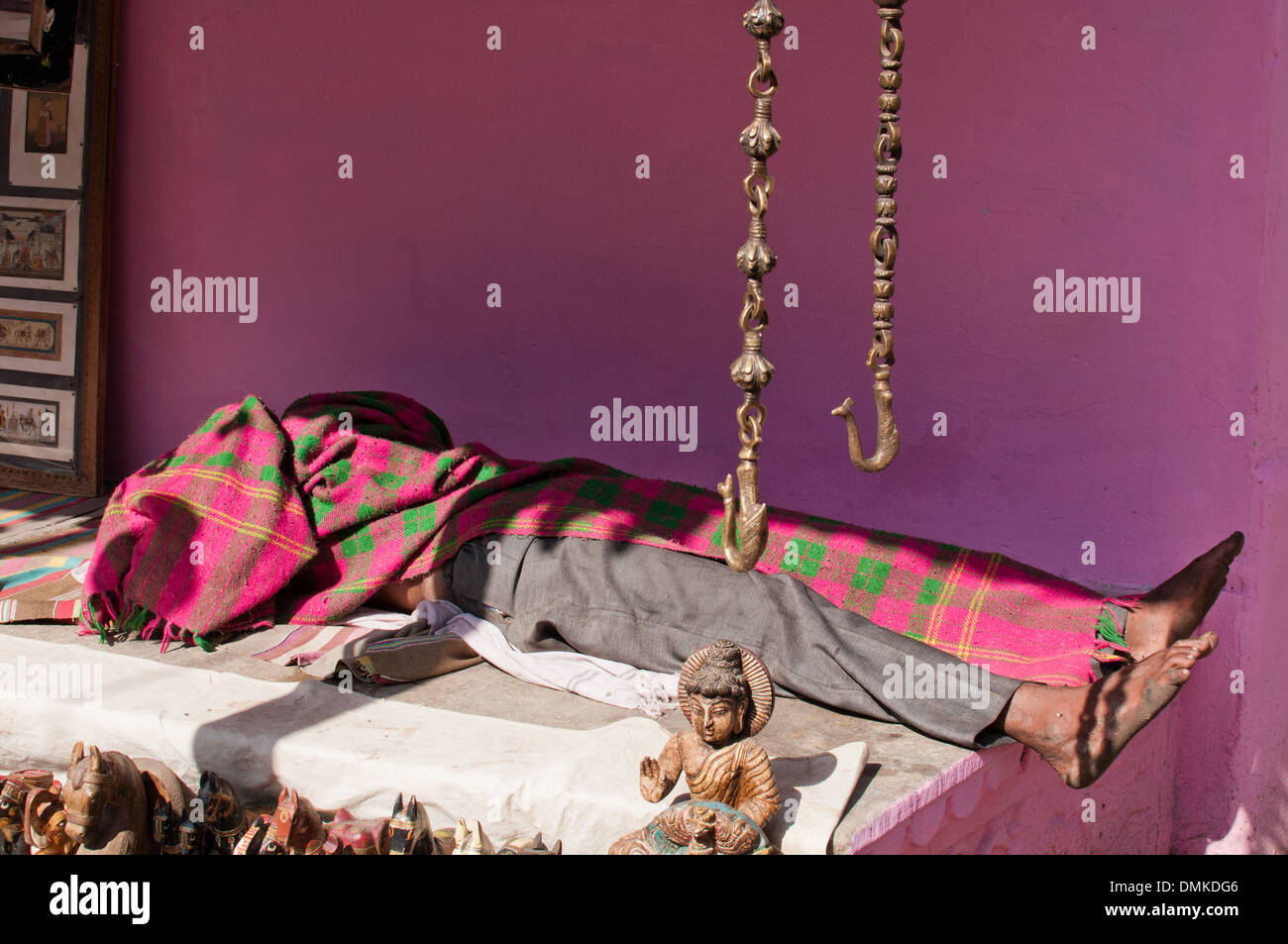 Un homme tout en dormant drapés dans une couverture rose sous un mur rose à Pushkar. Banque D'Images