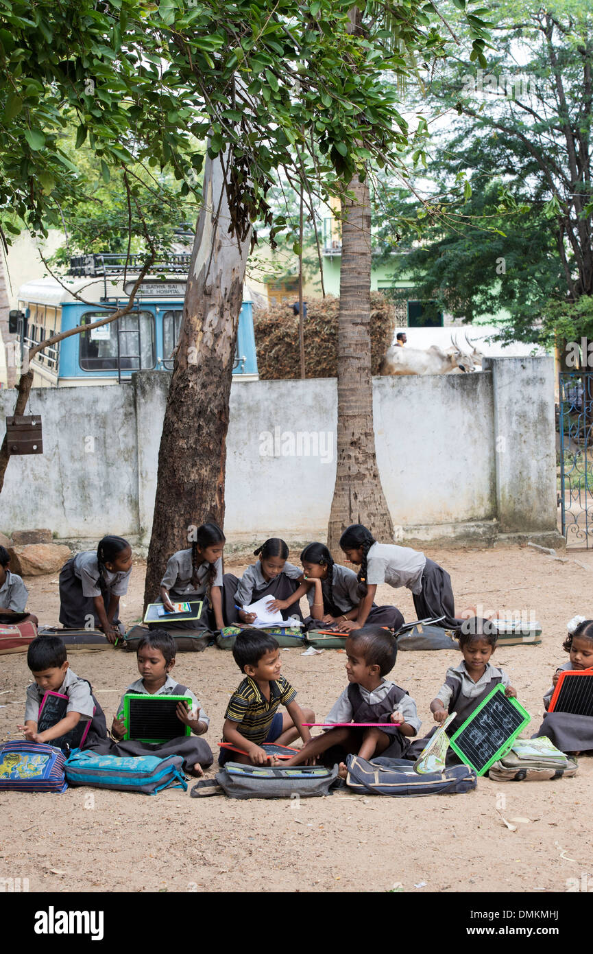 Les enfants de l'école village situé dans une classe en dehors de l'écriture sur un tableau noir comprimés. L'Andhra Pradesh, Inde Banque D'Images