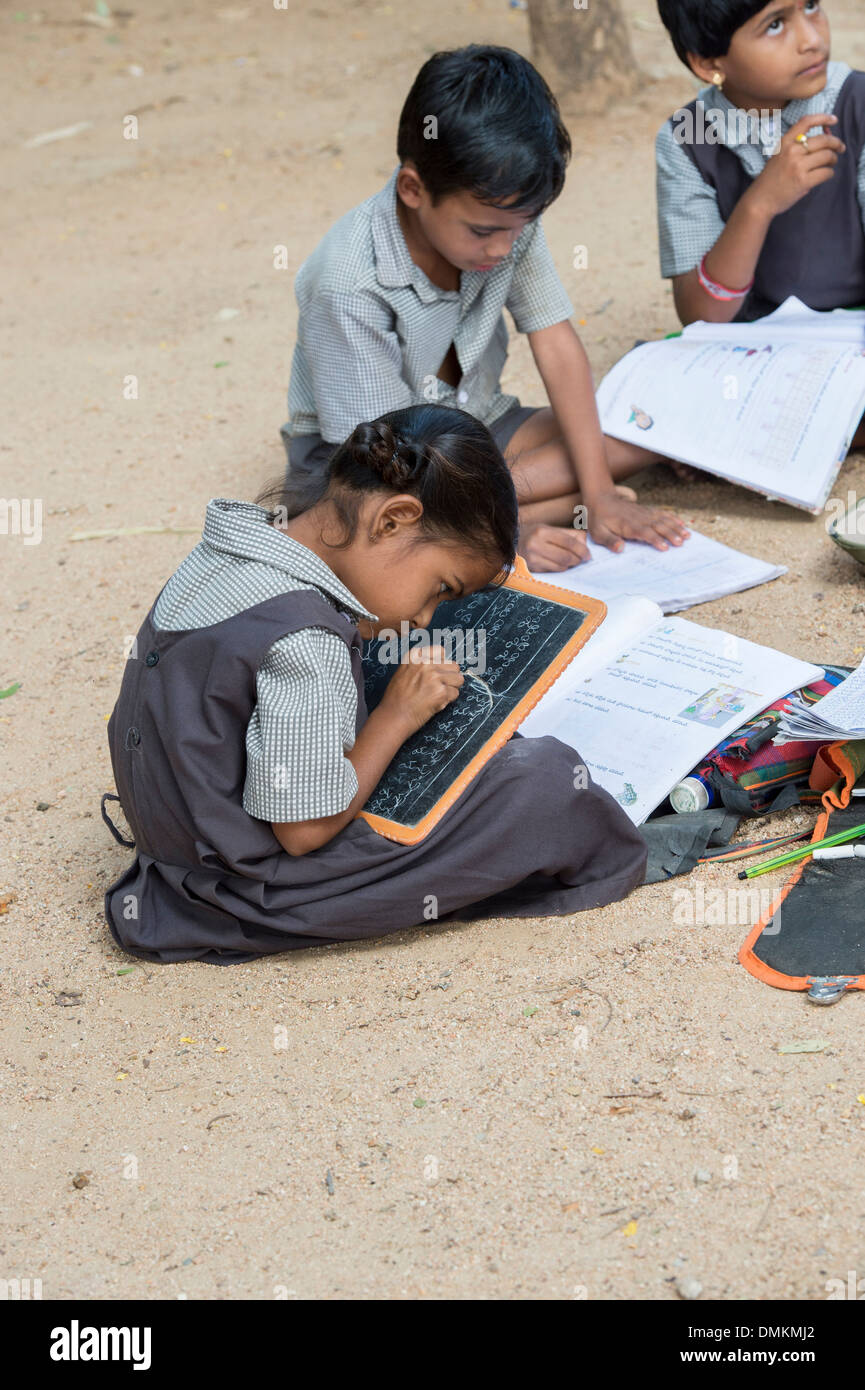 Les enfants de l'école village situé dans une classe en dehors de l'écriture sur un tableau noir comprimés. L'Andhra Pradesh, Inde Banque D'Images