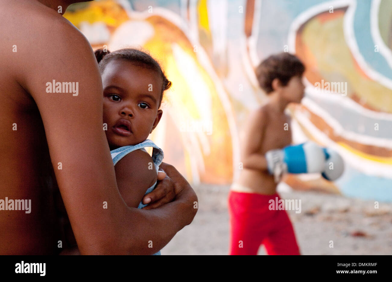Un jeune bébé cubains détenus par son père à regarder les garçons boxe sur la rue, Cienfuegos, Cuba, Caraïbes, Amérique Latine Banque D'Images