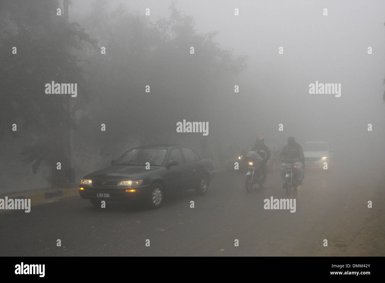 Lahore. 14Th Dec 2013. Déplacer les véhicules sur une route pendant un épais brouillard dans l'est de Lahore au Pakistan, le 16 décembre 2013. Lahore et ses environs ont été entièrement couverte par un épais brouillard, réduisant au minimum la visibilité et l'inquiétant vol, horaires de trains et de bus. Au moins sept personnes ont été tuées et 15 autres blessées dans des accidents liés au brouillard dans l'est du Pakistan la province du Pendjab, le lundi matin, la chaîne de télévision russe locale Geo signalés. Credit : Jamil Ahmed/Xinhua/Alamy Live News Banque D'Images