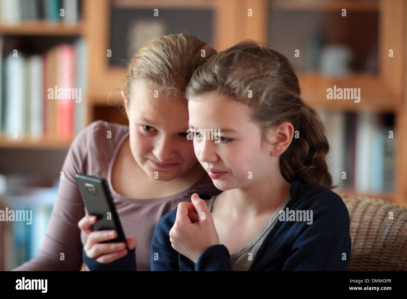 Les filles à la recherche d'un i phone dans une chambre ensemble Banque D'Images