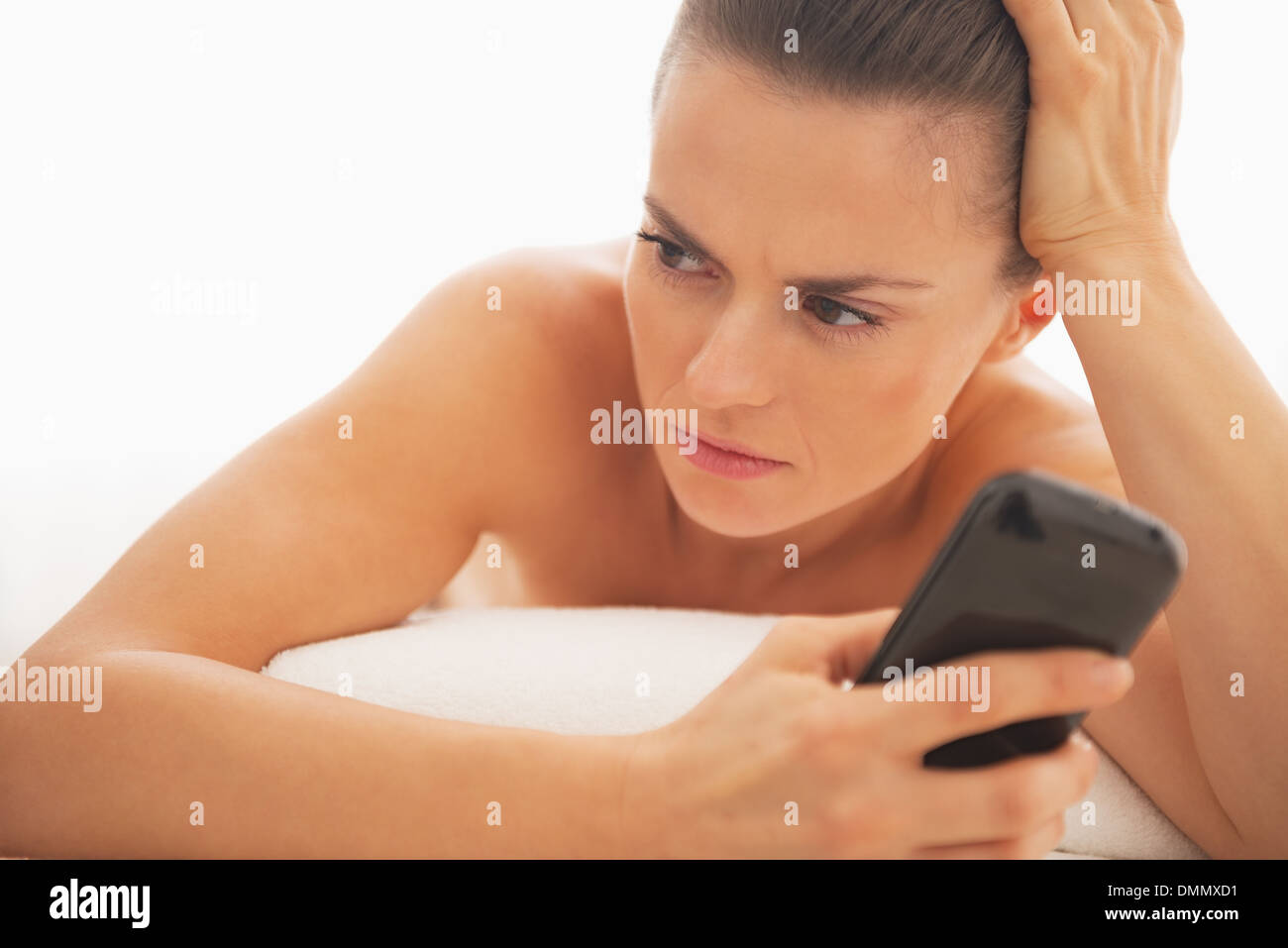 Jeune femme frustrée avec téléphone cellulaire portant sur table de massage Banque D'Images