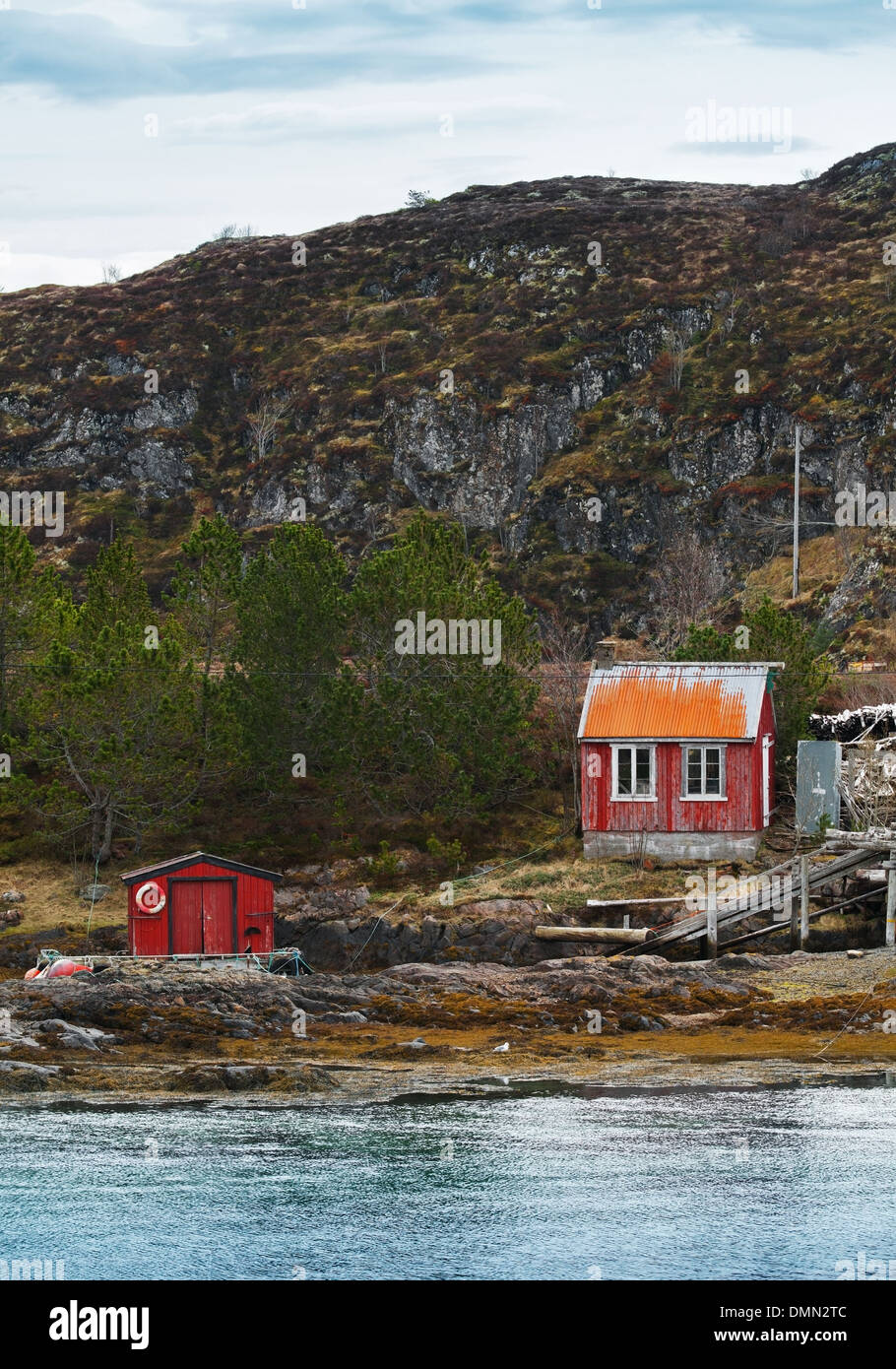 Vieilles maisons en bois rouge norvégienne sur la côte rocheuse Banque D'Images