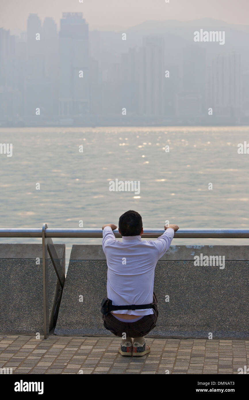 Jogger s'étend sur la promenade de Kowloon, Hong Kong. Banque D'Images