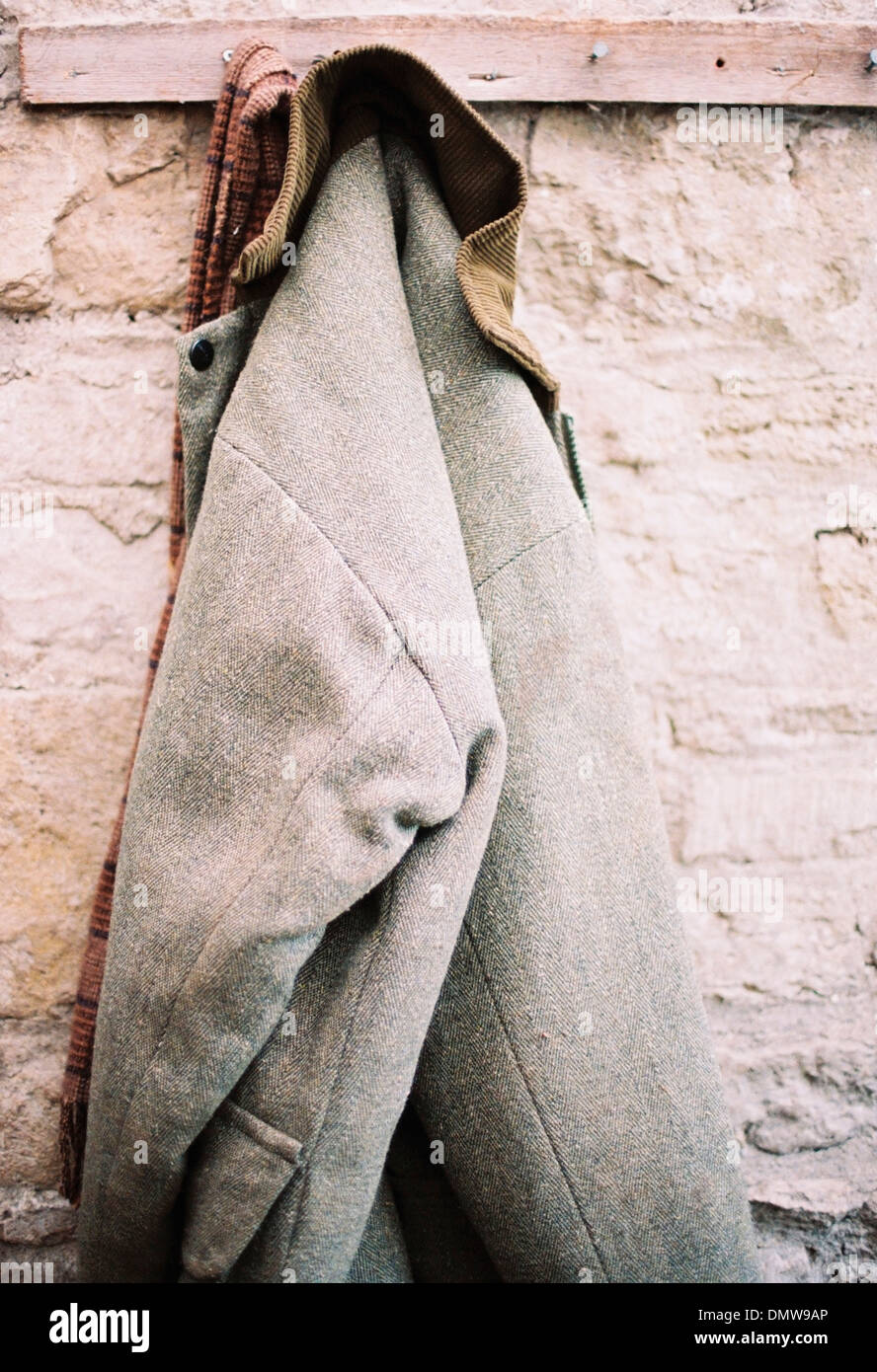 Une veste chaude traditionnelle avec col côtelé suspendue à un stylo sur un mur de pierre. Banque D'Images