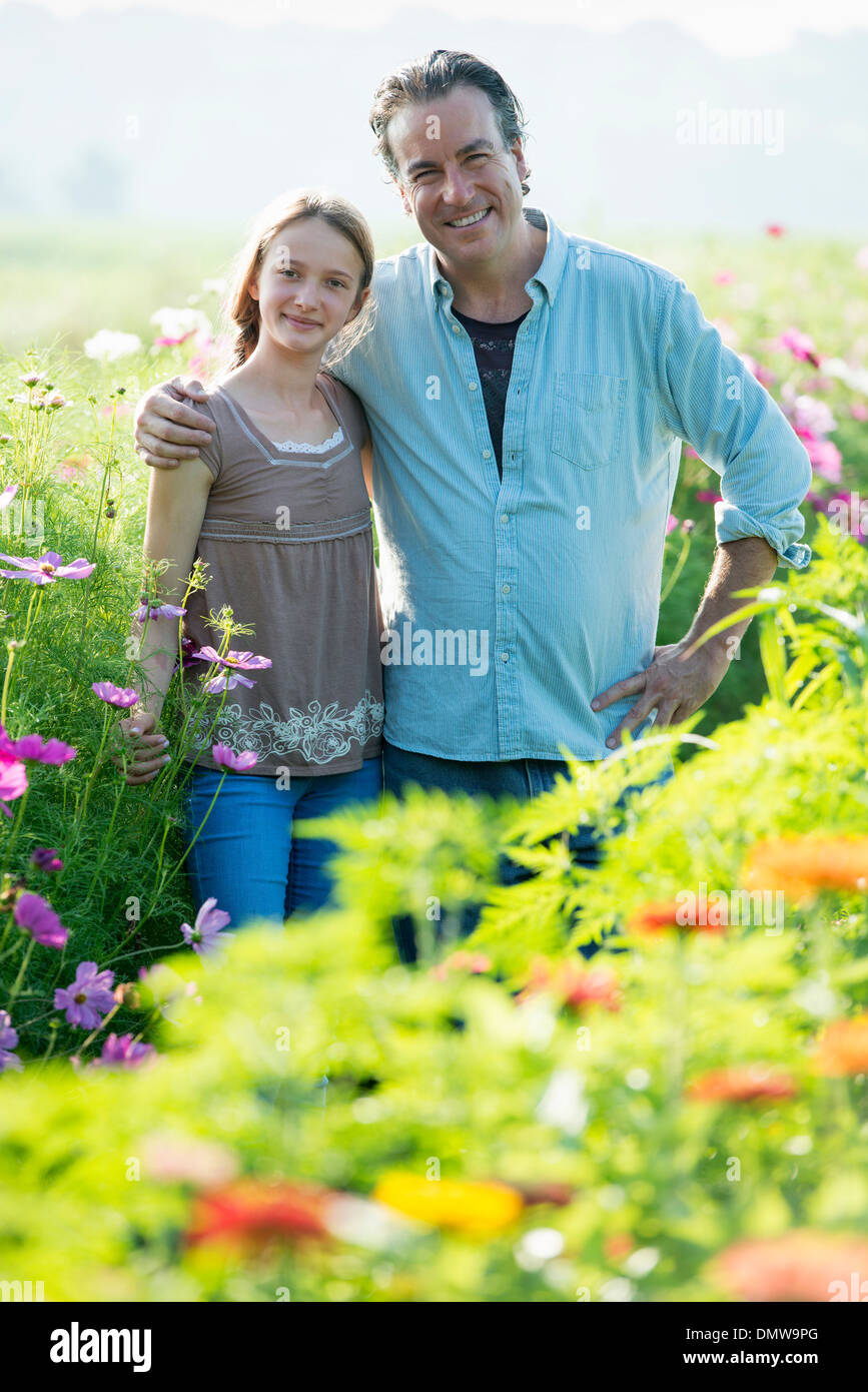 L'été sur une ferme biologique. Un homme et une jeune fille dans un champ de fleurs. Banque D'Images