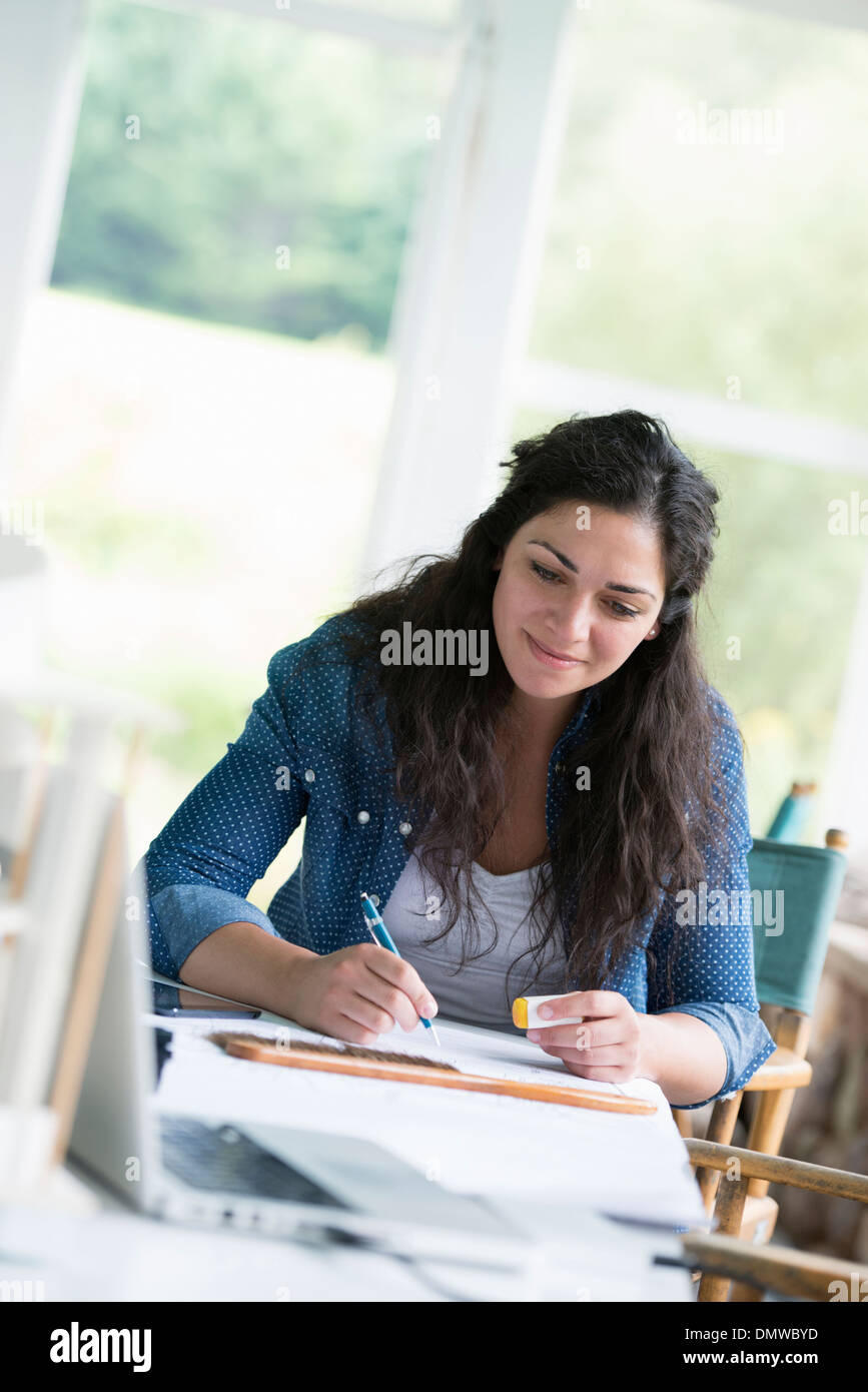 Une femme travaillant à une table à l'aide d'une tablette numérique. Banque D'Images