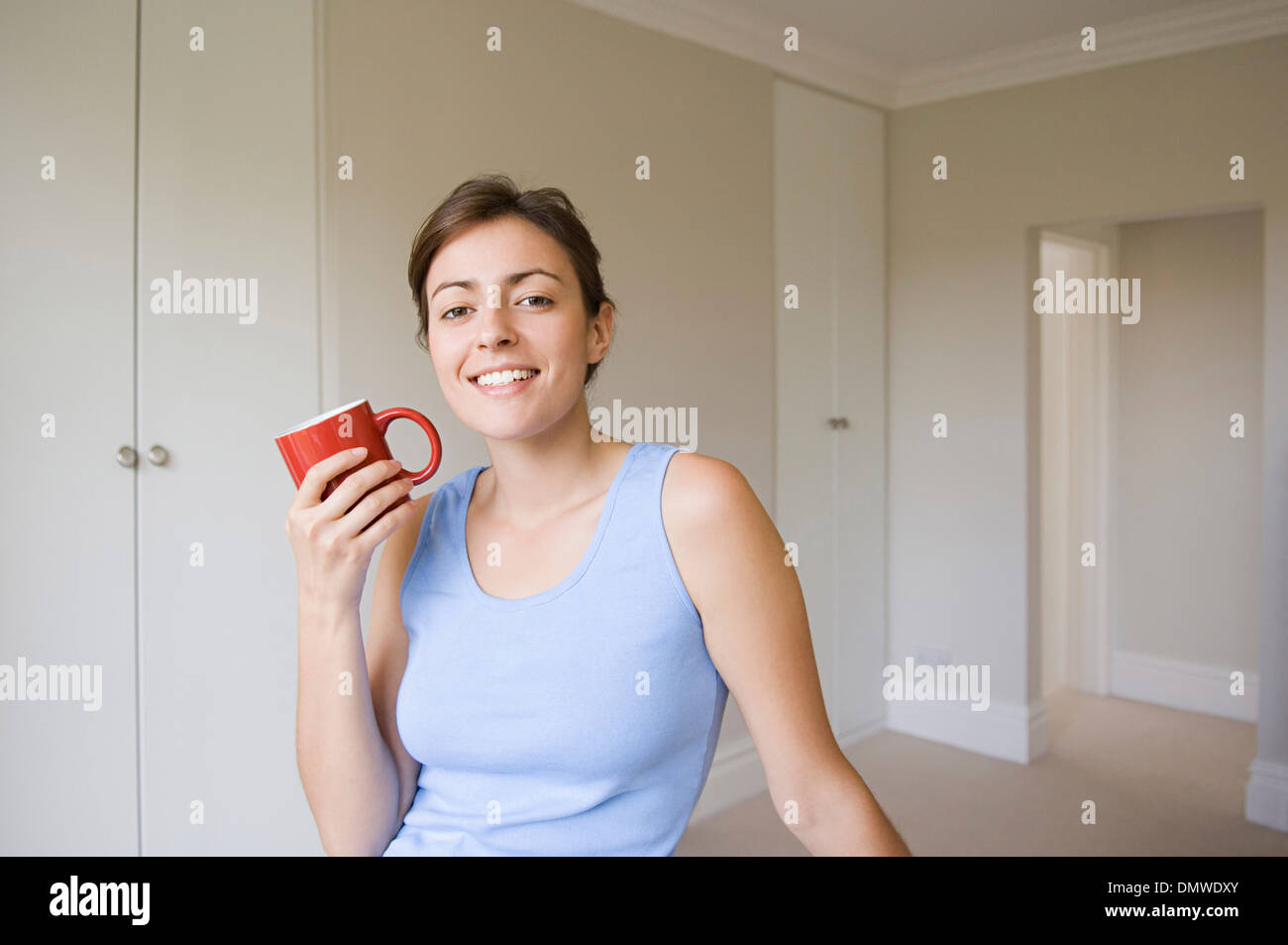 Une femme portant un haut bleu assis tenant une tasse de la Chine rouge. Banque D'Images